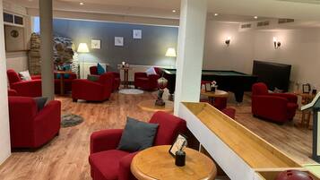 A lounge area with red sofas, a pool table, and a bowling ball rack.