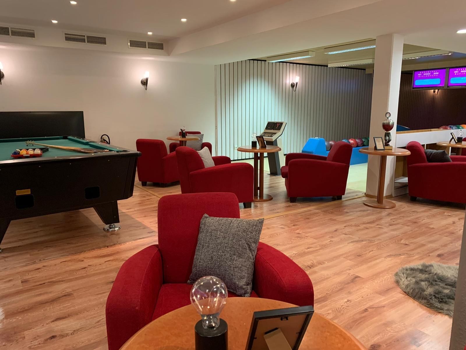 Un espacio interior moderno con mesa de billar, sofás rojos e instalación de billar.