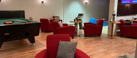 Un espacio interior moderno con mesa de billar, sofás rojos e instalación de billar.