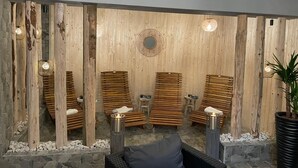 A spa area with wooden slatted benches, stone walls, and a central decorative wall piece.