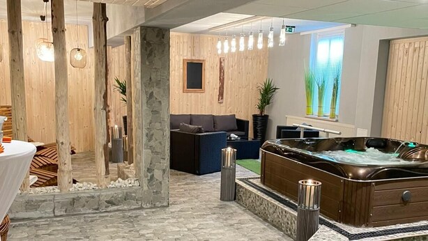 A spa area with a stone floor, wooden ceiling, and a massage table.