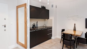 Une cuisine moderne avec des meubles de couleur sombre, une porte à cadre en bois, un pare-feu en carrelage et un coin repas comprenant une table et des chaises.