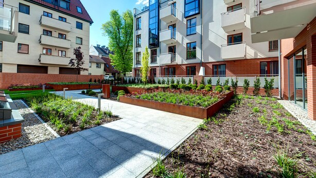Un immeuble d’appartements moderne doté de nombreux balcons, d’une cour aménagée et d’une façade en briques.