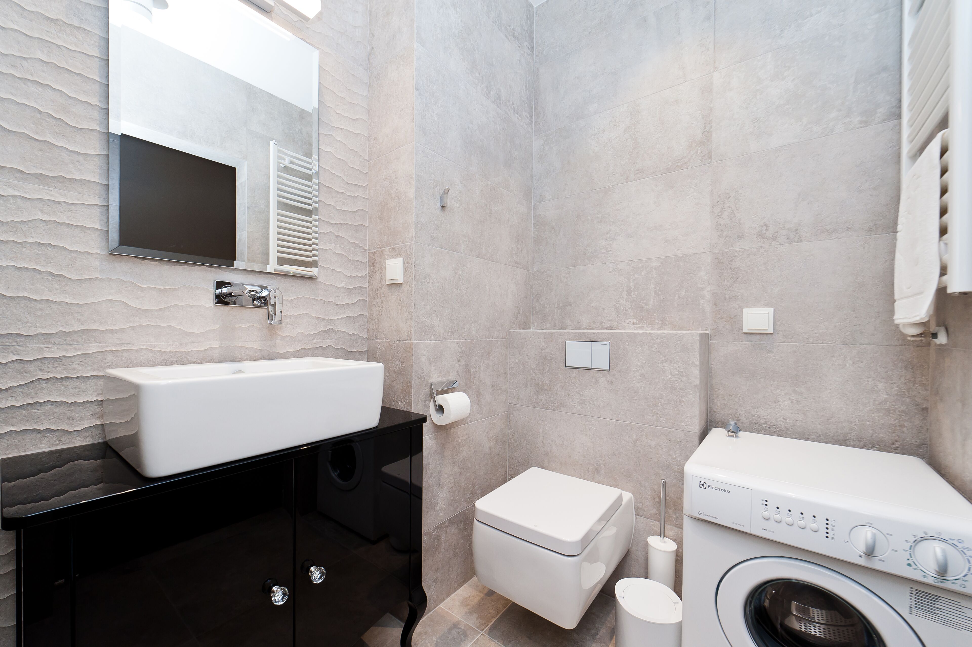 A modern bathroom with a large sink, toilet, and washing machine.