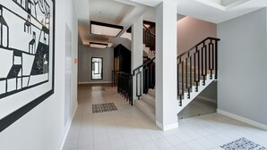 Un intérieur moderne avec un escalier, un tapis à motifs et un mur orné d’un motif abstrait en noir et blanc.
