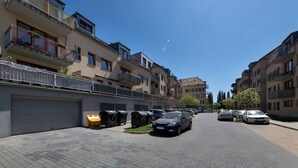 Una calle residencial con edificios de apartamentos modernos, una vía pavimentada y coches estacionados.