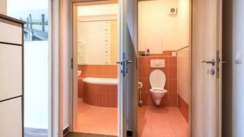 A bathroom with a bathtub, toilet, and a shower area.