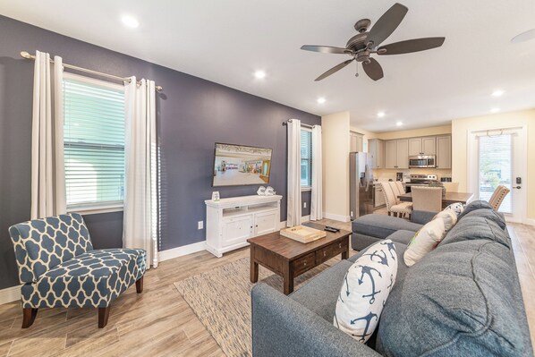 A living room with a sofa, armchair, coffee table, and a ceiling fan.