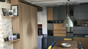 Uma cozinha moderna com armários de madeira, uma mesa de jantar com cadeiras e uma luminária pendente.