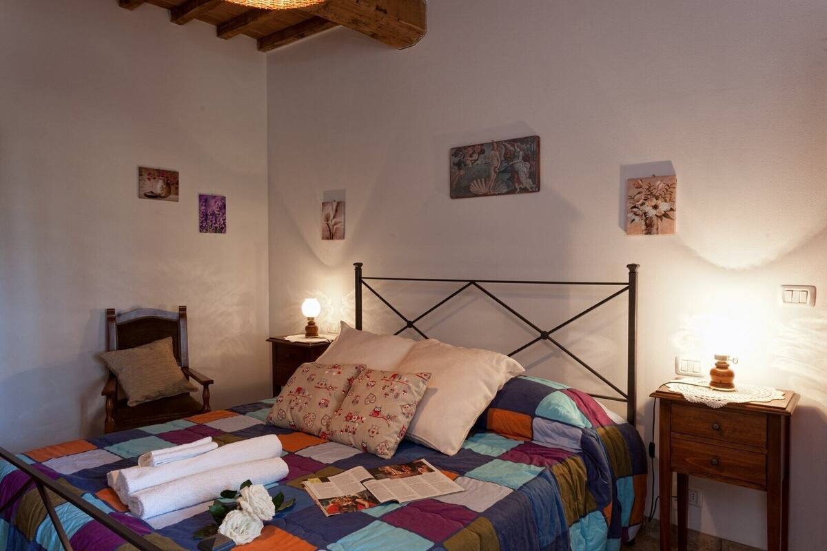 Un dormitorio con una cama, una silla, una mesita de noche y una mesilla auxiliar.