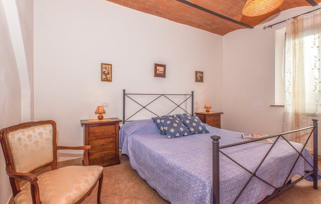 Een slaapkamer met een bed, een stoel, een nachtkastje en een lamp.