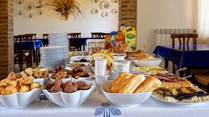 A buffet table with various food items and a dining area with tables and chairs. - San Lorenzo Agriturismo (Buonconvento)