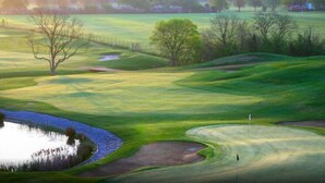 A golf course with a pond, trees, and a fence. - Northwick Park Apartment (Harrow)