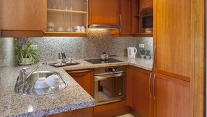 A kitchen with granite countertops, stainless steel appliances, wooden cabinets, and a built-in microwave. - TORRE GRAND LUXE APARTMENT (El Port de la Selva)