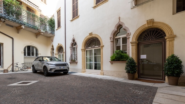 A cobblestone street leading to a building with a white facade, arched windows, and a gated entrance. - AD Verona Flat (Verona)