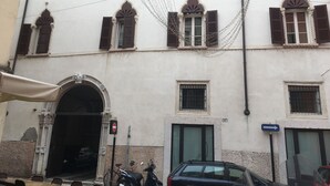 A building with multiple windows, some with shutters, and a barred entrance. There are signs indicating no entry and directional arrows. - AD Verona Flat (Verona)