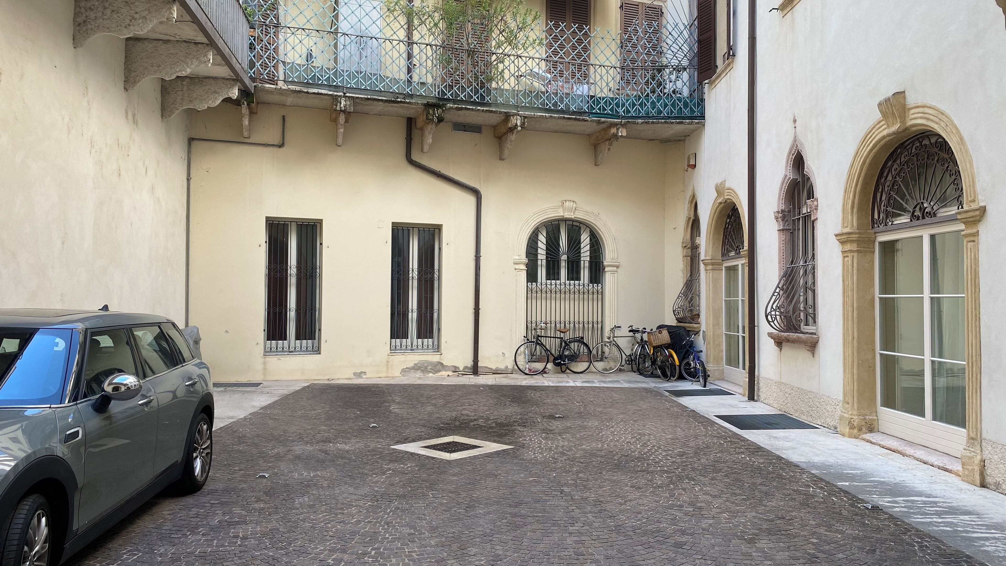 A narrow cobblestone street with a parked car and bicycles.