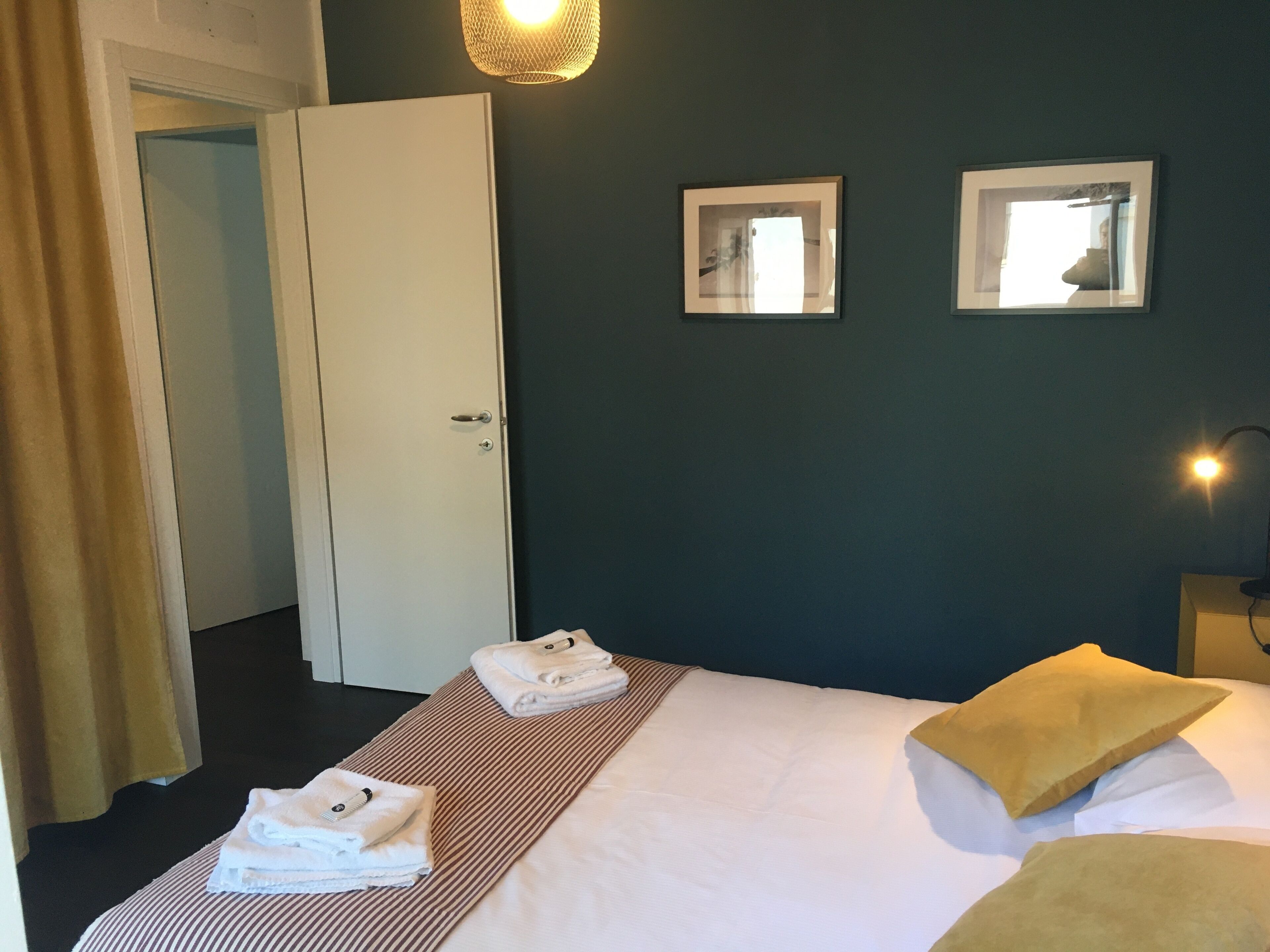 A hotel room with a bed, two bedside tables, a door, and two wall-mounted mirrors.