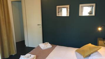 A hotel room with a bed, two bedside tables, a door, and two wall-mounted mirrors.