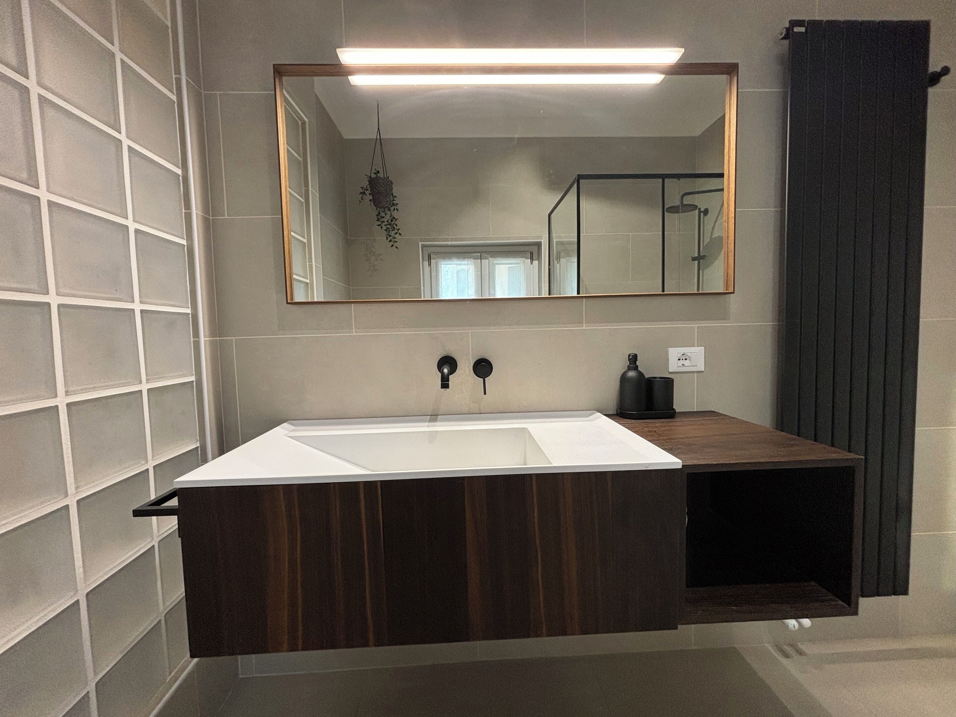 A bathroom with a large mirror, a white sink, and a dark wooden vanity.