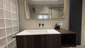 A bathroom with a large mirror, a white sink, and a dark wooden vanity.