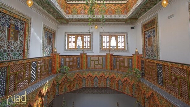 An ornate interior with intricate tile work, arched windows, and a patterned ceiling. - Riad Fes Madaw (Fes)