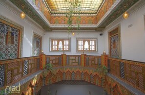 An ornate interior with intricate tile work, arched windows, and a patterned ceiling. - Riad Fes Madaw (Fes)