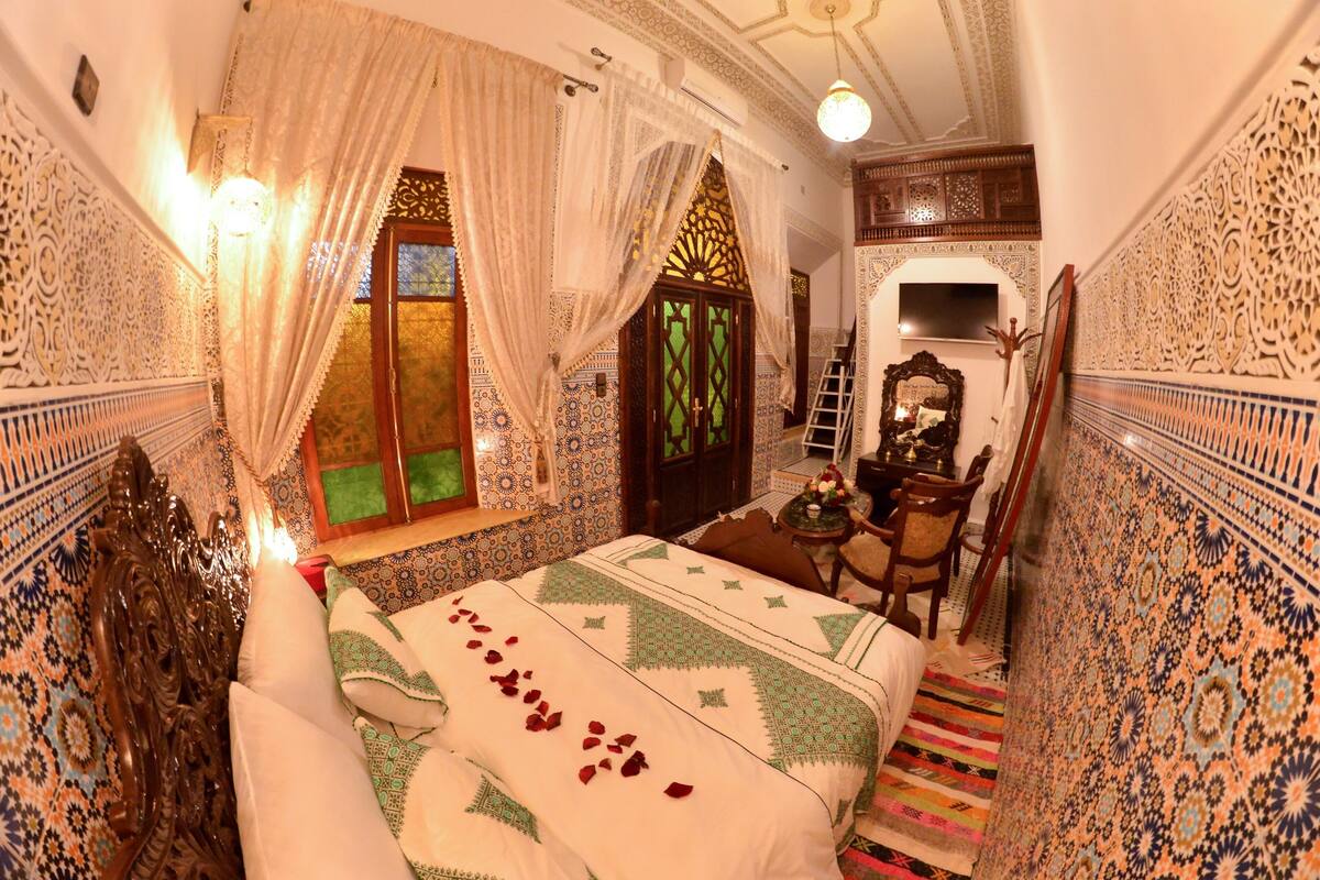 A traditional room with a bed, a desk, and a mirror.