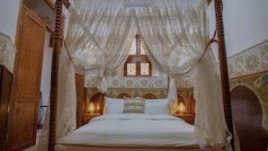 A four-poster bed with a canopy, ornate wooden headboard, and patterned wall decor. - Riad Fes Madaw (Fes)