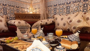 A traditional Moroccan dining setup with a table set for a meal, including bread, olives, and a jug of orange juice. - Riad Fes Madaw (Fes)