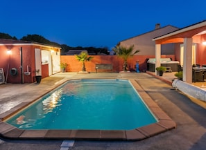 A swimming pool with a surrounding patio area, a bench, and a hot tub. - Homerez - Villa in Carcassonne (Carcassonne)
