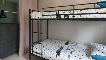 Un lit superposé avec une couvre-lit à motifs géométriques, un tapis de sol noir et un luminaire suspendu.