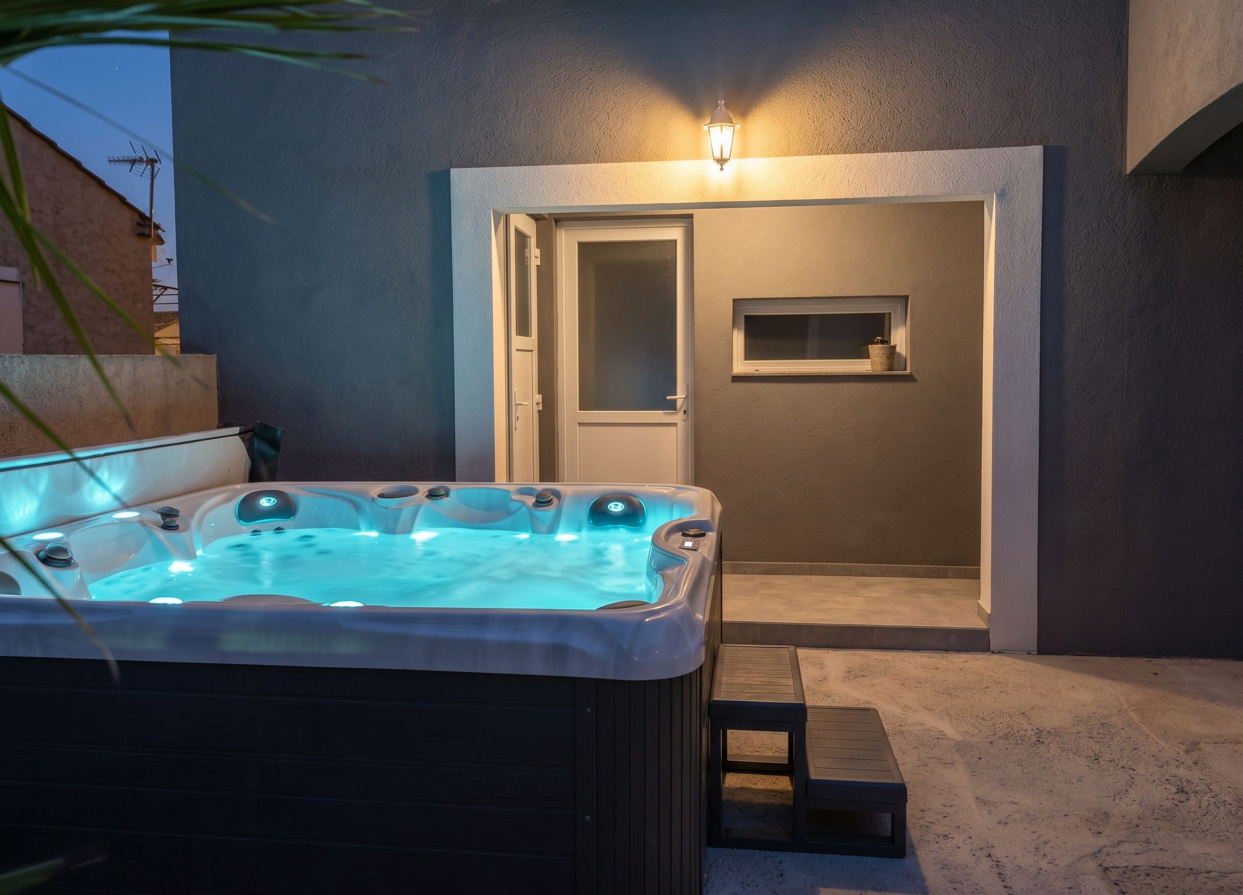 A hot tub with a control panel, a door leading to a covered area, and a small window with a picture frame.
