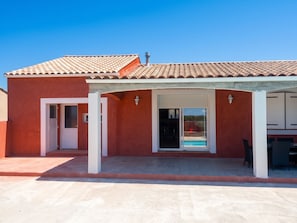 A building with a red exterior, a tiled roof, and a covered patio area. - Homerez - Villa in Carcassonne (Carcassonne)