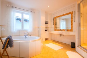 A modern bathroom with a large bathtub, a double sink vanity, and a walk-in shower. - Appartement Bosek (Wagrain)