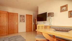 A dining area with a wooden table, chairs, a television, and a framed picture on the wall. - Appartement Bosek (Wagrain)