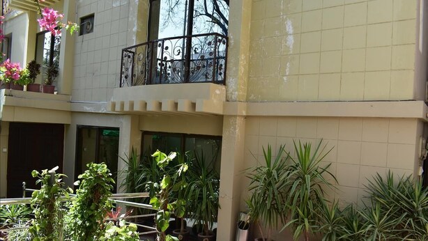 A courtyard with potted plants and a balcony with a wrought iron railing. - Savoy Inn (Islamabad)