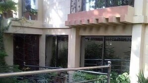 A courtyard with a metal railing, potted plants, and a building with large windows. - Savoy Inn (Islamabad)