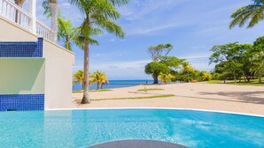 Piscina com vista para a praia e palmeiras.