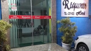 A hotel entrance with a glass door, a signboard with the hotel's name and contact number, and a white car parked outside. - Requinte Hotel Itabuna (Itabuna)
