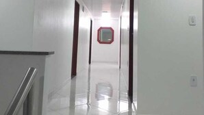 A long, narrow hallway with white walls and a shiny tiled floor. - Requinte Hotel Itabuna (Itabuna)