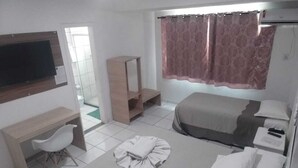 A hotel room with a bed, a desk, a chair, a TV, and a window with curtains. - Requinte Hotel Itabuna (Itabuna)