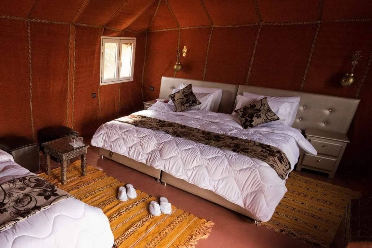 A spacious tent-style room with a large bed, a small table, and a window.
