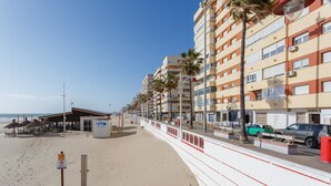 A beachside promenade with a row of multi-story buildings, a sandy beach, and a small beachside restaurant.