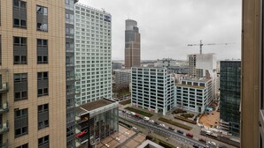 A cityscape with modern buildings, including a high-rise with a glass facade and a construction site with a crane. - Green Wood Apartments Platinum Towers (Warsaw)