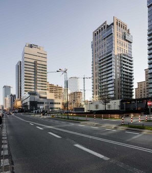A city street with modern buildings, including a bank and a high-rise residential building.