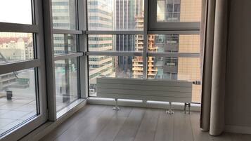 Una habitación con un ventanal grande, piso de madera y un banco blanco.