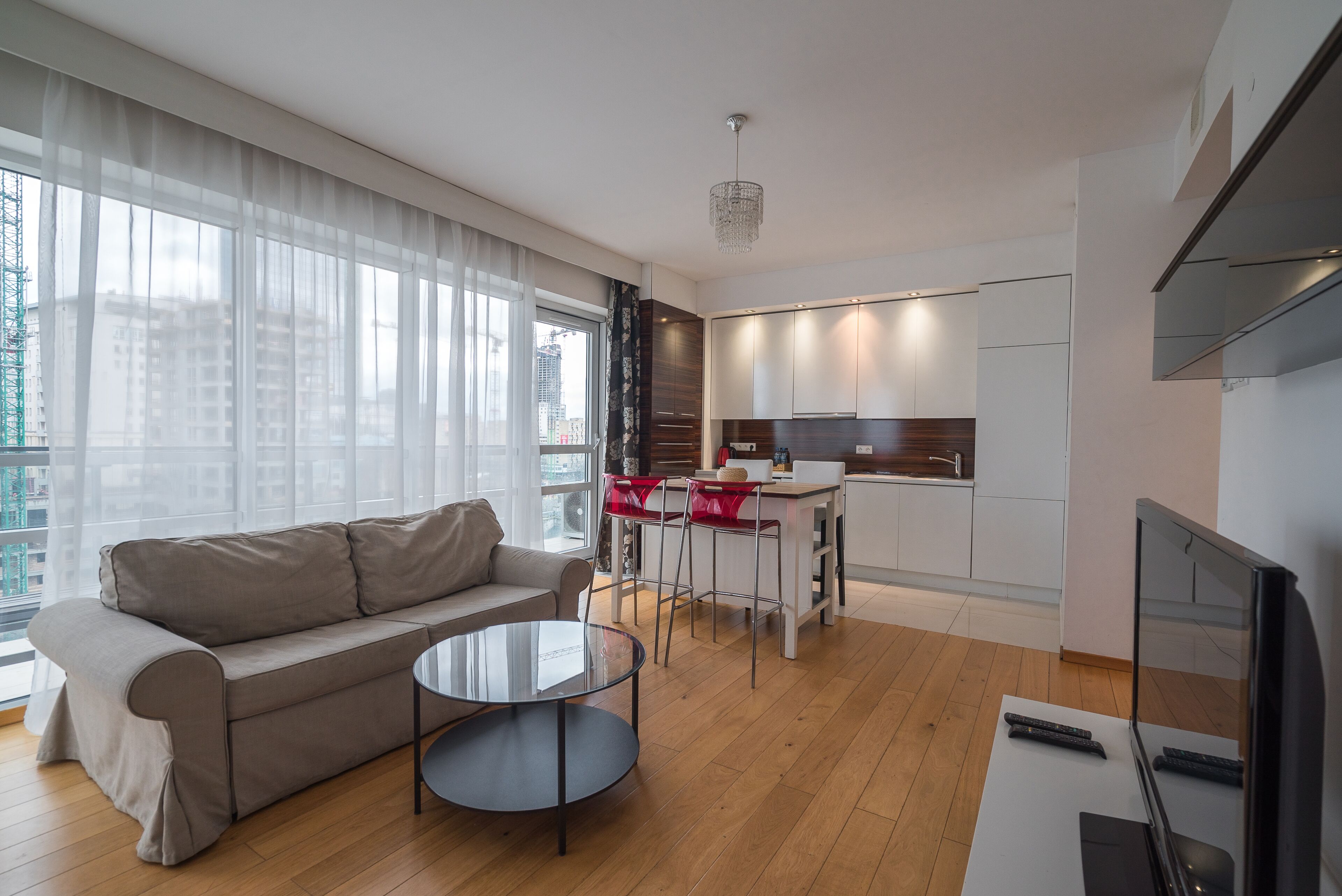 Una sala de estar moderna con un sofá, una mesa de centro de vidrio y un televisor.