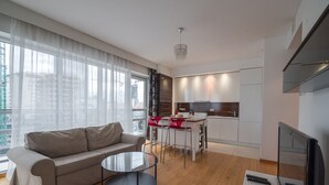 A modern living room with a sofa, a glass coffee table, and a TV. - Green Wood Apartments Platinum Towers (Warsaw)