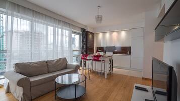 Una sala de estar moderna con un sofá, una mesa de centro de vidrio y un televisor.
